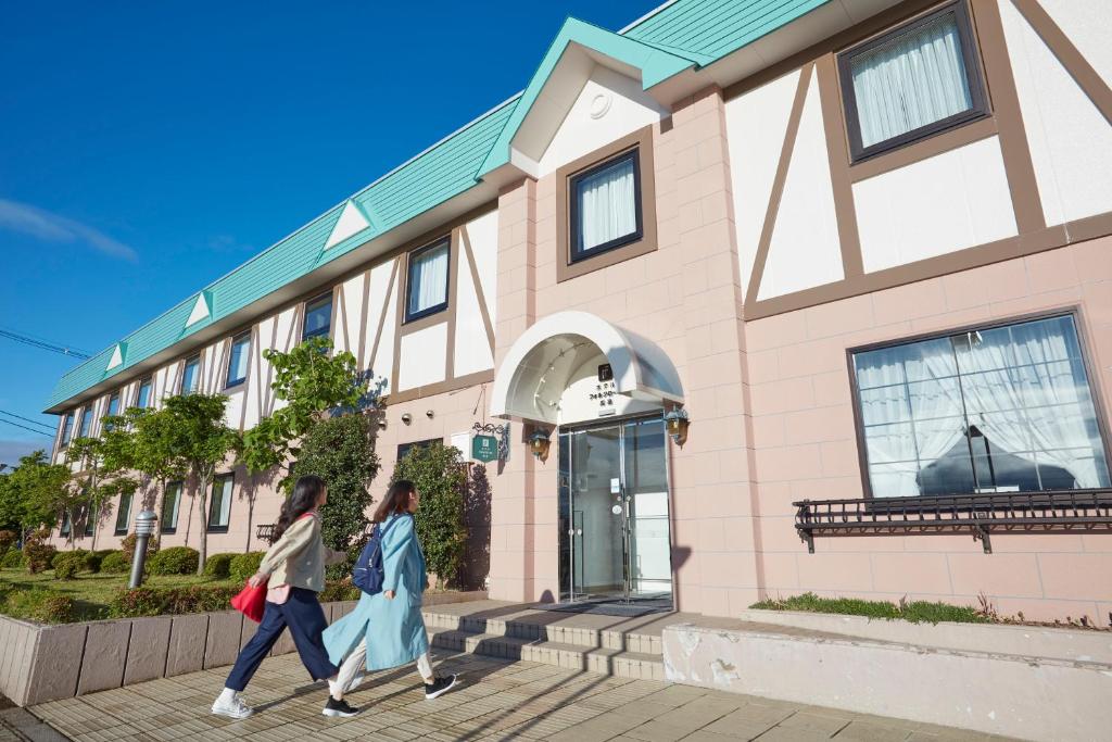 two women walking in front of a building at Hotel Folkloro Takahata in Takahata