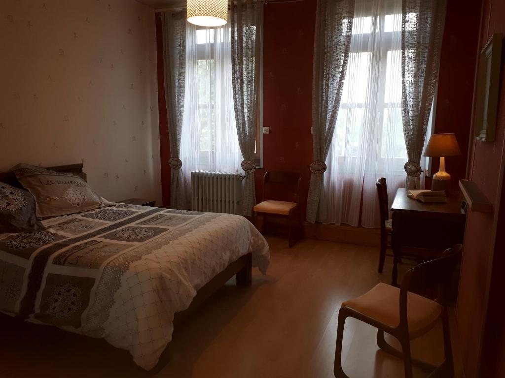 a bedroom with a bed and a desk and windows at Chambre du Nouvion in Le Nouvion-en-Thiérache