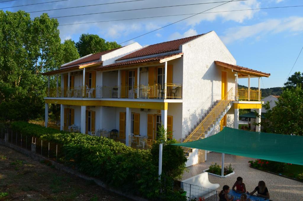 une maison avec des personnes assises devant elle dans l'établissement Yellow House, à Kavos