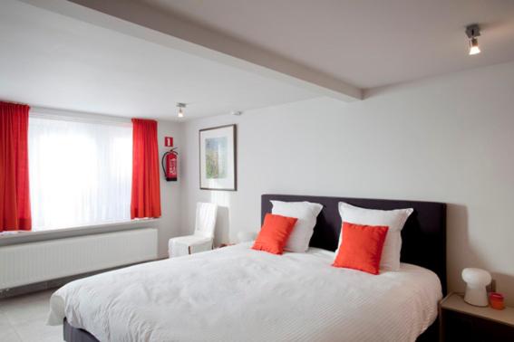 een slaapkamer met een groot wit bed met oranje kussens bij BBMalpertuus in Kruisstraat