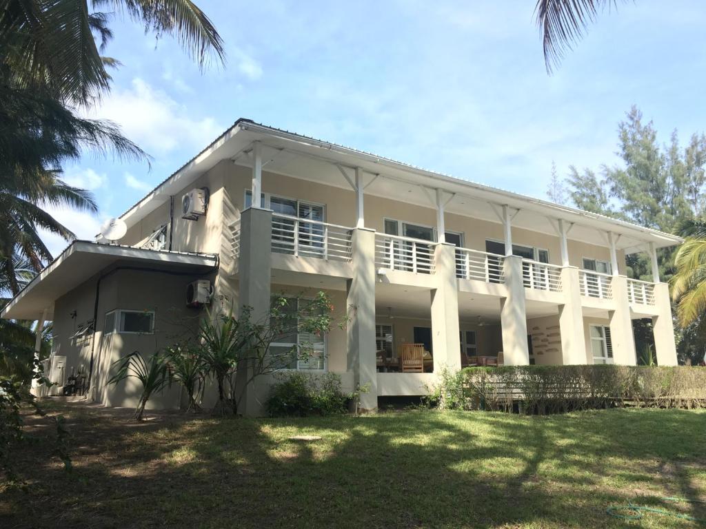 ein großes weißes Gebäude mit Palmen davor in der Unterkunft Barra Beach Villa in Inhambane