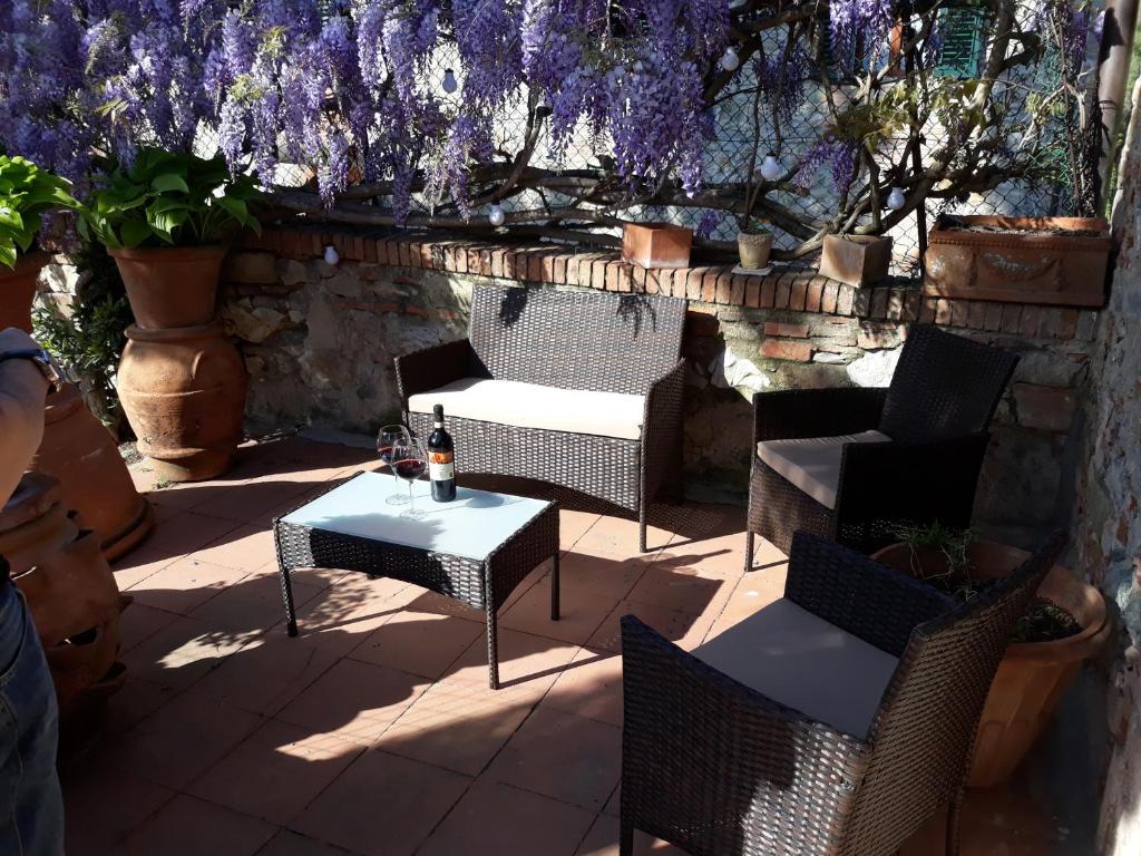 un patio con sillas, una mesa y flores púrpuras en Dimora Ricceri, en Impruneta