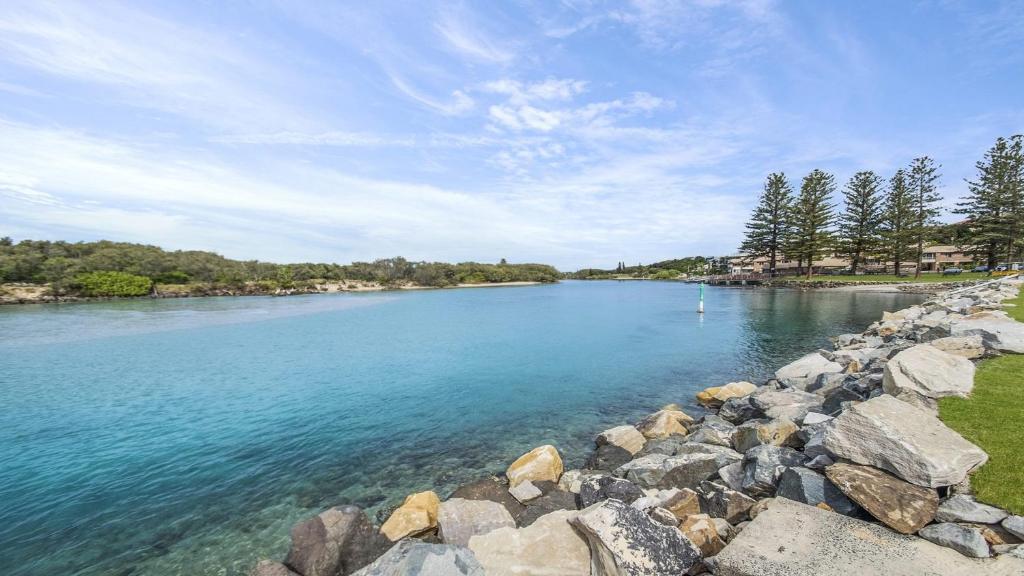 a large body of water with rocks and trees at Heritage Pines Apartment by Kingscliff Accommodation in Kingscliff