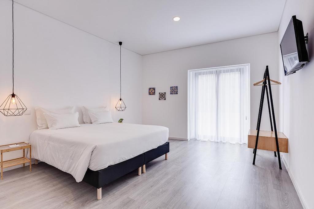 a white bedroom with a bed and a television at Ovar Apartments by Aqualeisure in Ovar