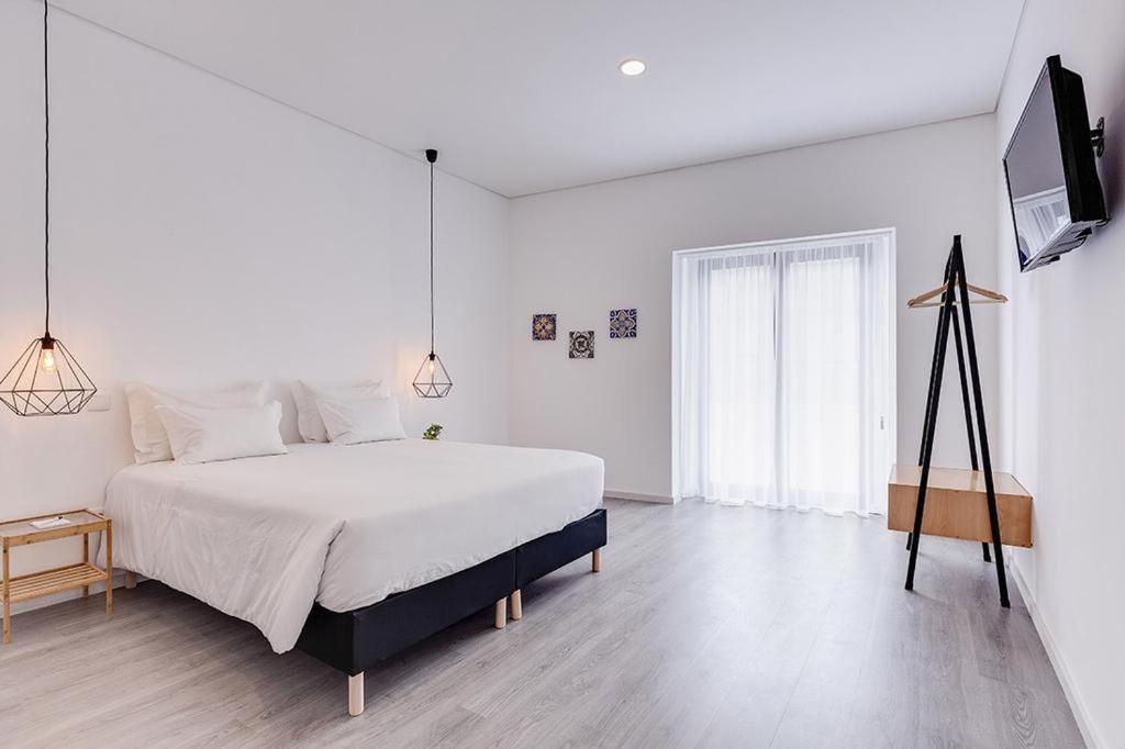 een witte slaapkamer met een bed en een televisie bij Ovar Apartments in Ovar