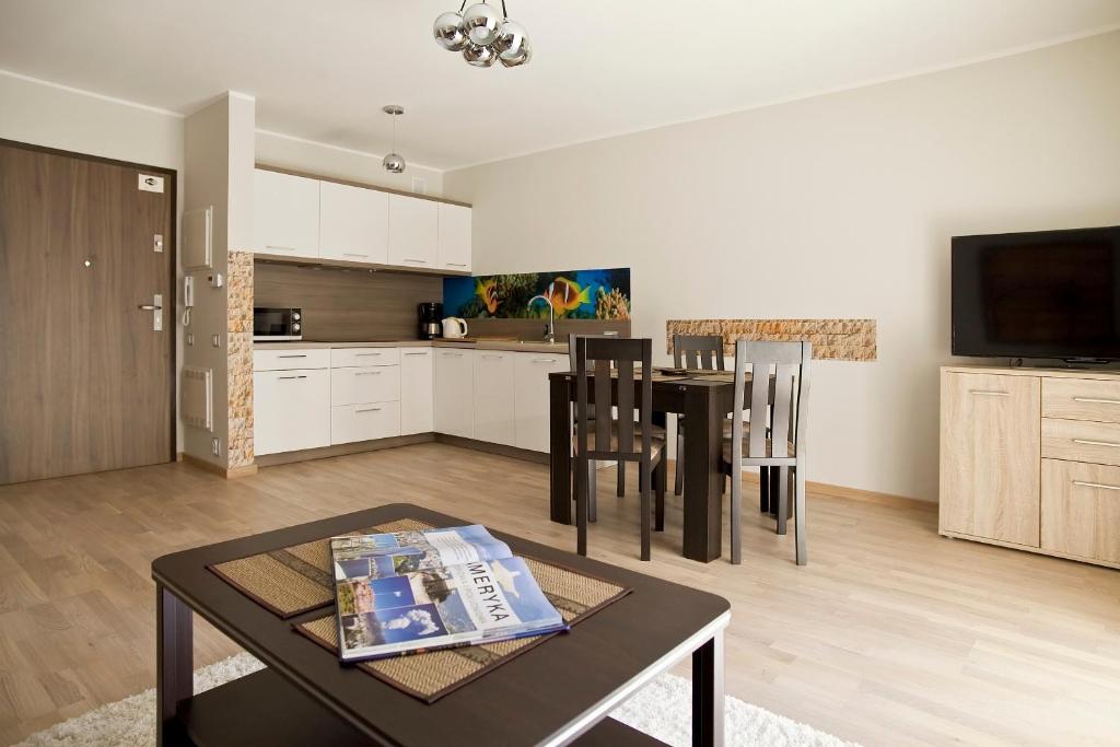 kuchnia i salon ze stołem i krzesłami w obiekcie Rezydencja Park Rodzinna w mieście Mielno