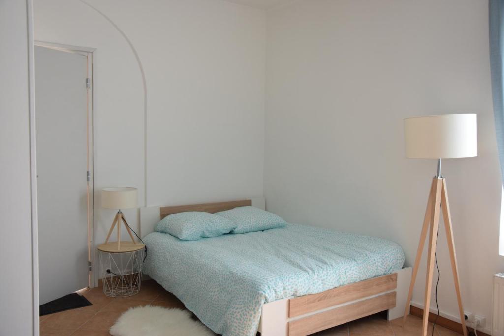 ミリ・ラ・フォレにあるJoli Studio Plein Centre de Milly la Forêtのベッドルーム1室(青い毛布とランプ2つ付)