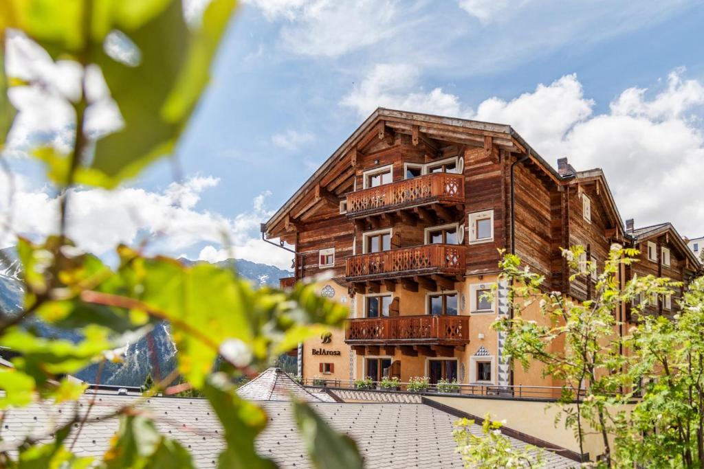 - un bâtiment en bois avec des balcons sur le toit dans l'établissement BelArosa Suiten & Wellness, à Arosa