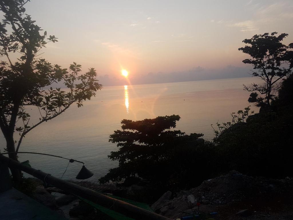 a sunset over the water with trees in the foreground at Chabalay Resort in Ko Tao