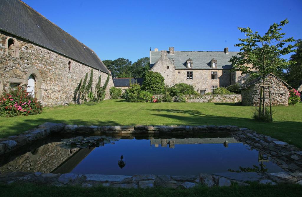 a large stone building with a pond in front of it at Le Manoir de La Fieffe in Cherbourg en Cotentin