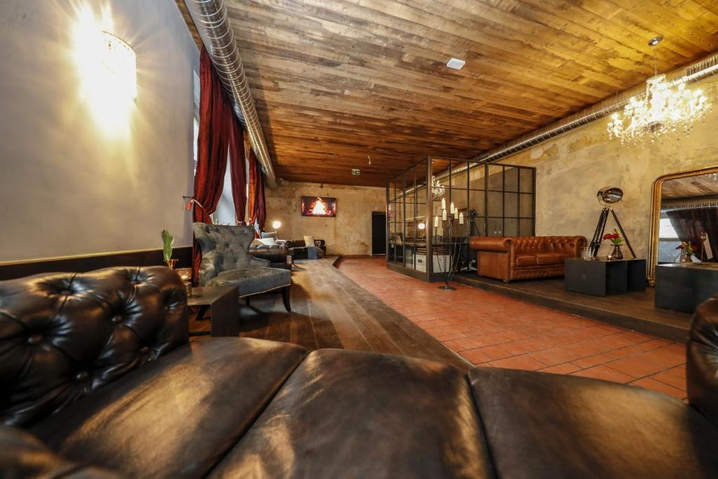 a living room with leather furniture and a wooden ceiling at Hotel Lehenerhof in Salzburg
