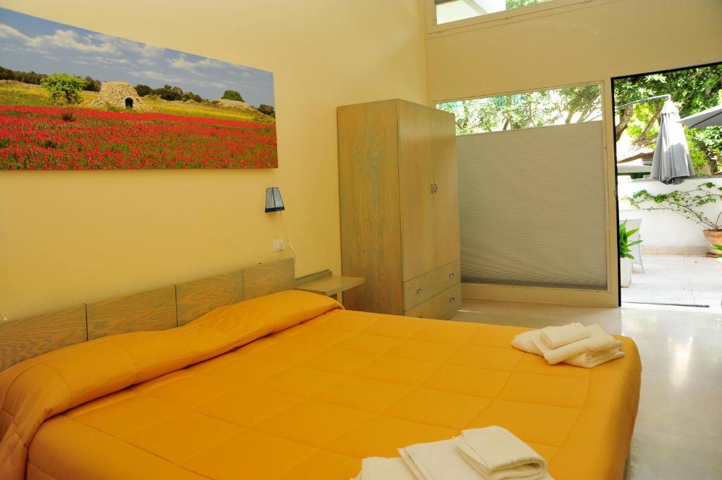 una camera da letto con un letto arancione e un dipinto sul muro di Cala Dei Normanni - Camere sul Lungomare a Otranto