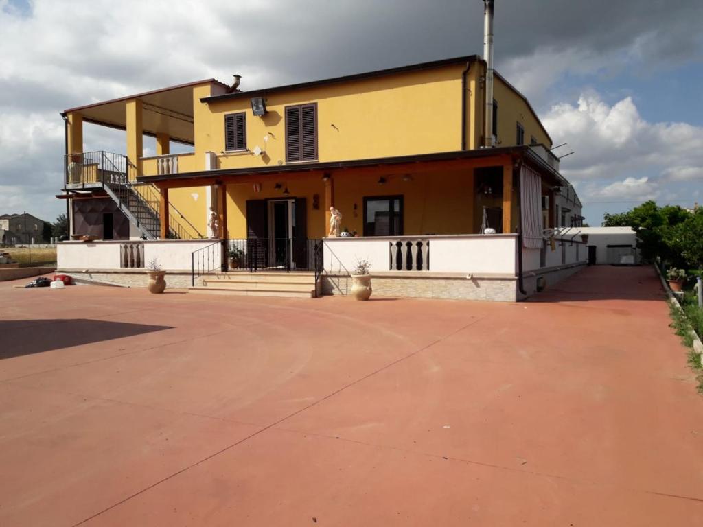 ein großes gelbes Gebäude mit einer Veranda und einer Treppe in der Unterkunft Villa Maria in Marconia