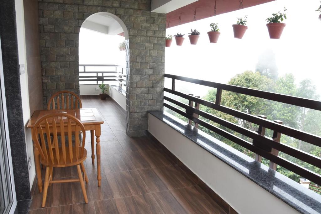 balcone con tavolo e sedie in camera di Nirvana Retreat a Kurseong