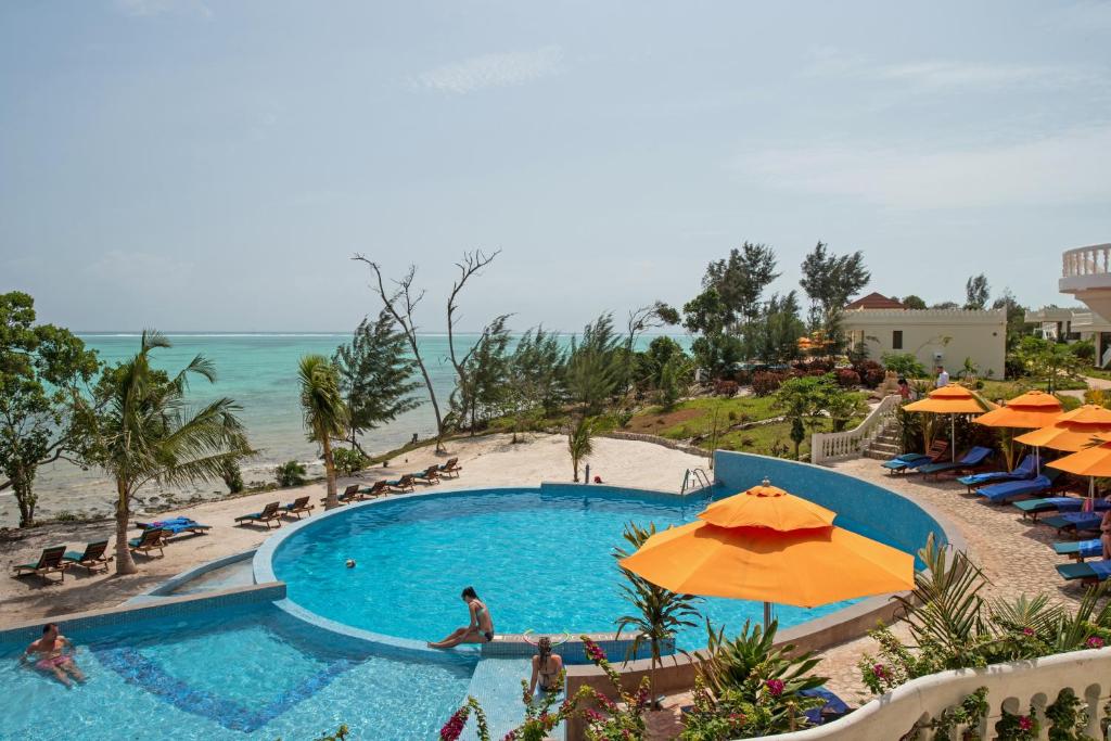 einen Pool mit Sonnenschirmen und Strand in der Unterkunft Moja Tuu The Luxury villas & Nature Retreat in Kiwengwa
