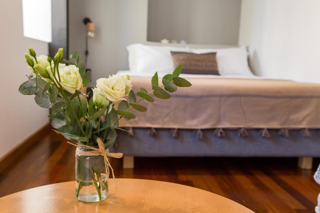 a vase with white roses on a table in a bedroom at Sofita Hotel in Preveza