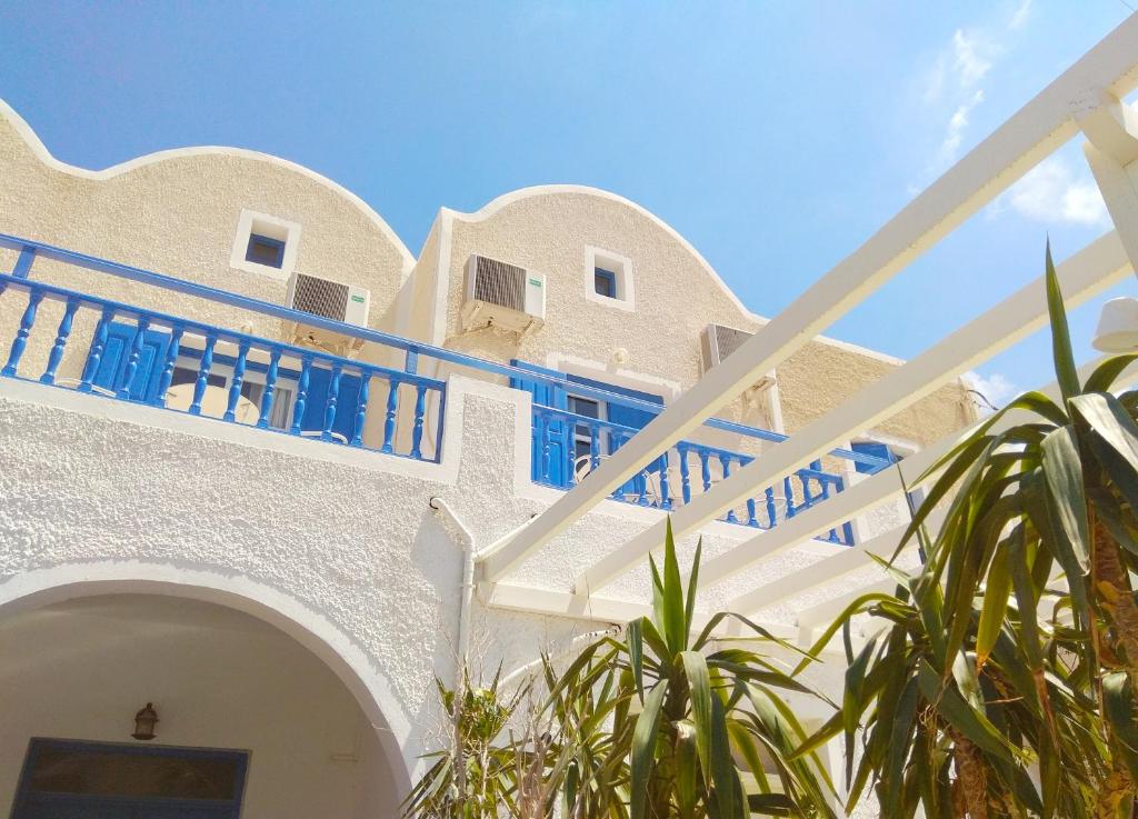 a white building with blue balconies and a staircase at Villa Dioni in Kamari