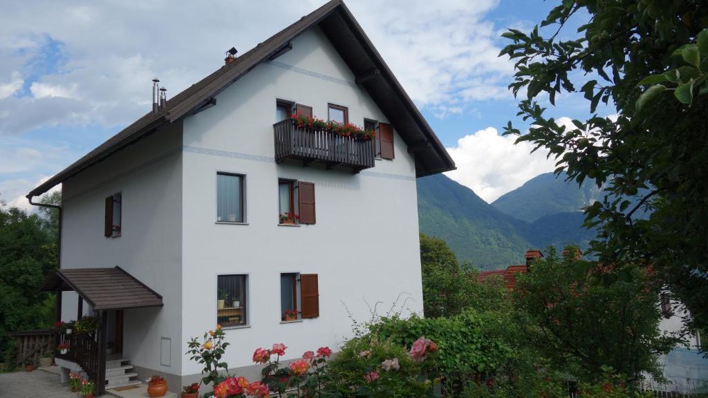 a white house with a balcony and mountains in the background at Apartment Makuc in Bovec