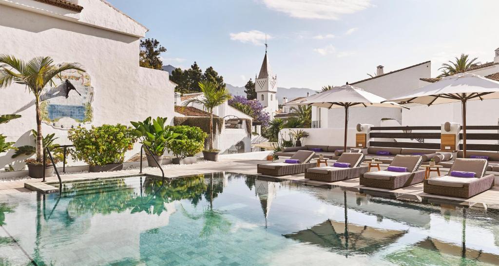 a pool with lounge chairs and a building with a church at Nobu Hotel Marbella in Marbella