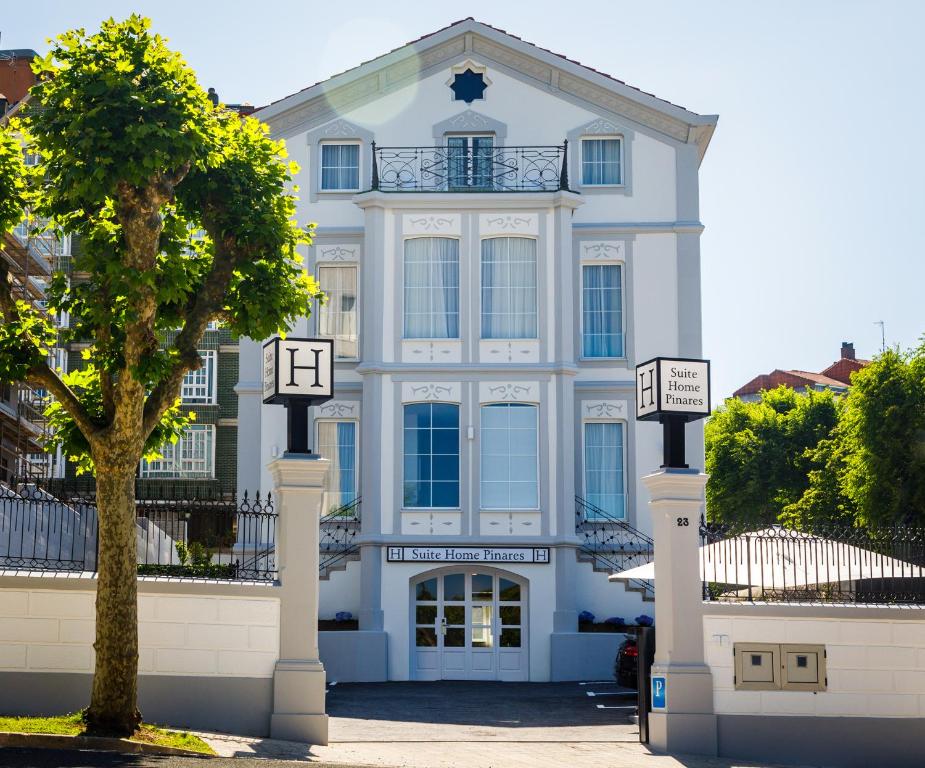 uma casa branca com uma árvore em frente em Suite Home Pinares em Santander