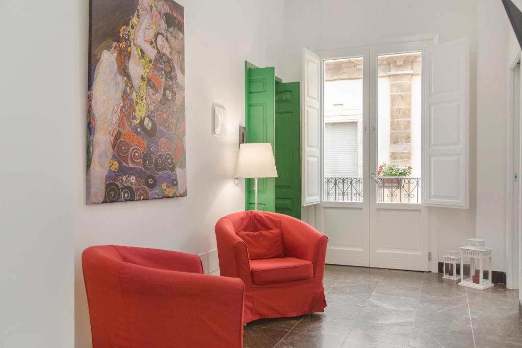 una sala de estar con 2 sillas rojas y una pintura en Shalai Relais Apartment, en Pachino