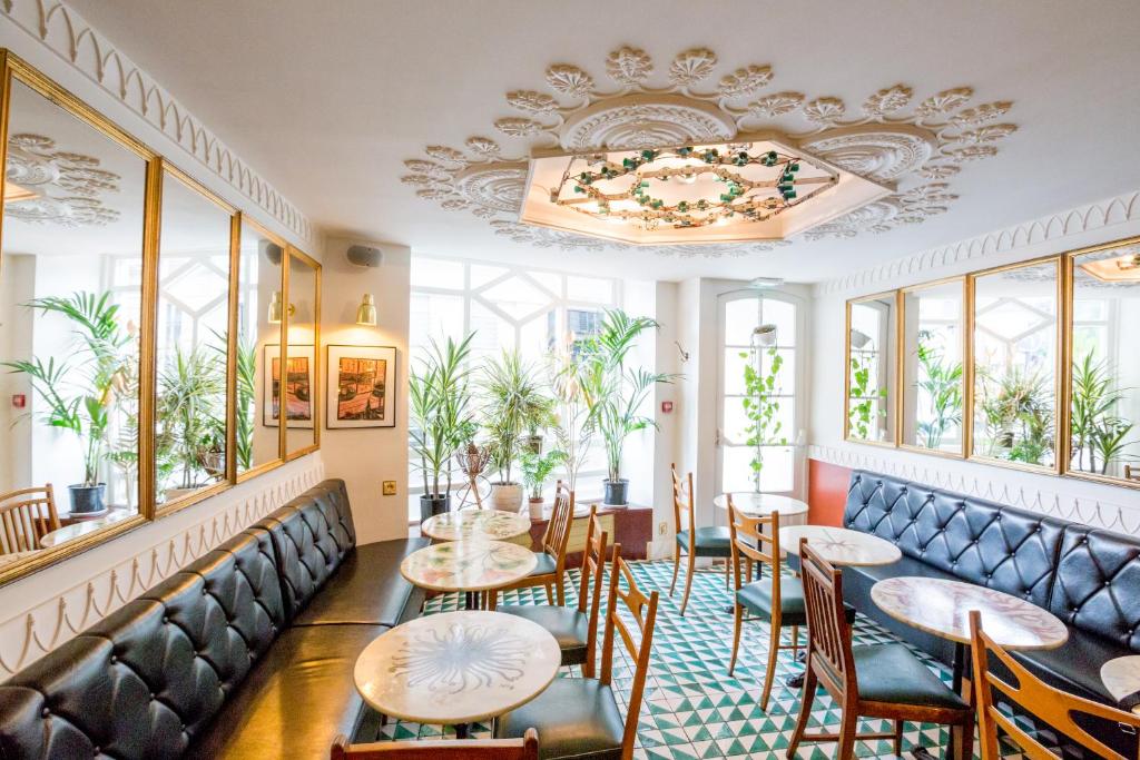 un restaurant avec des tables, des chaises et des fenêtres dans l'établissement Hôtel du Temps Paris, à Paris
