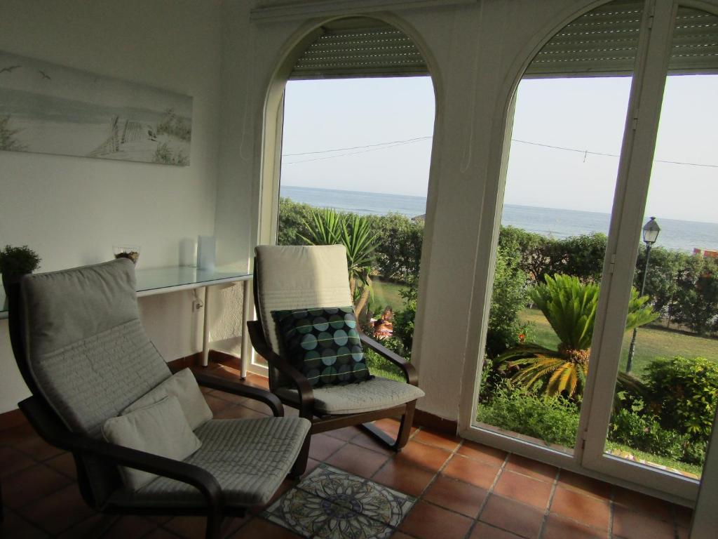 a living room with two chairs and a view of the ocean at Malaga Paradise Beach in Torre de Benagalbón