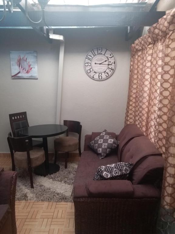 uma sala de estar com um sofá e um relógio na parede em Avon Apartments em Lilongwe