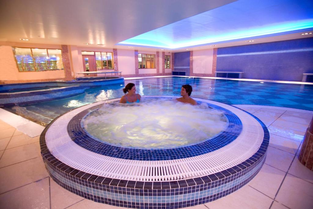 a man and woman in a hot tub in a swimming pool at Hillgrove Hotel, Leisure & Spa in Monaghan