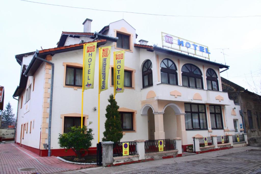un edificio blanco con banderas delante en Garni Hotel PBG en Subotica