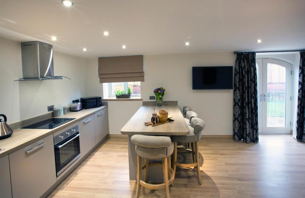 a kitchen with a kitchen island with bar stools at Woodspurge Cottage, Drift House Holiday Cottages in Astbury