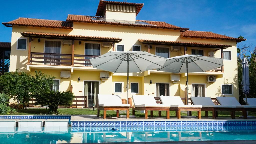 a villa with a swimming pool and umbrellas at Pousada das Garças in Saquarema