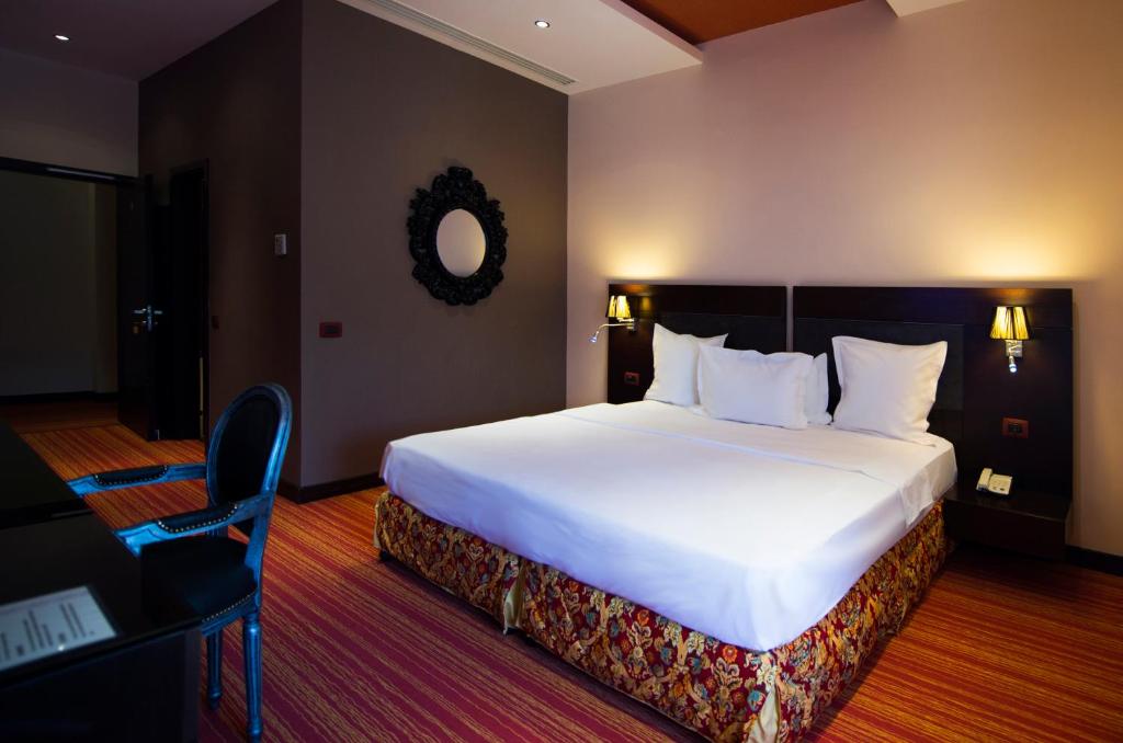 Cette chambre comprend un grand lit blanc et une chaise. dans l'établissement Nane Hotel, à Gyumri