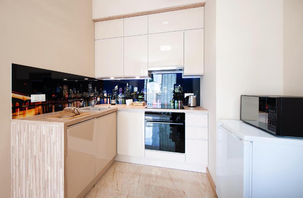 a kitchen with white cabinets and a microwave at Awangarda Home Apartment in Warsaw