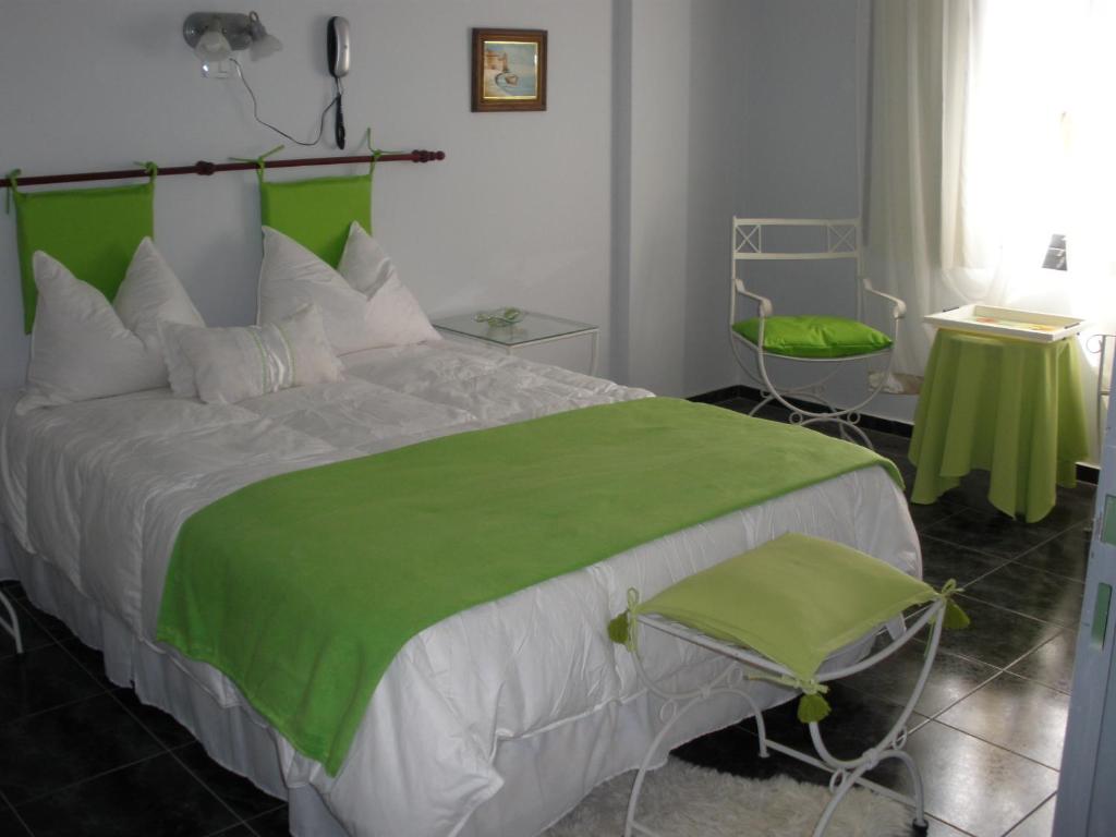 ein Schlafzimmer mit einem großen Bett und einer grünen Decke in der Unterkunft Noria Hotel in Villa Carlos Paz