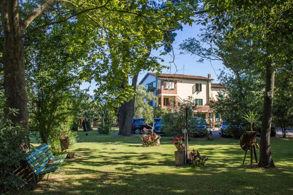 een park met een gebouw en bomen en een bank bij B&B Da Pio in Pietrasanta