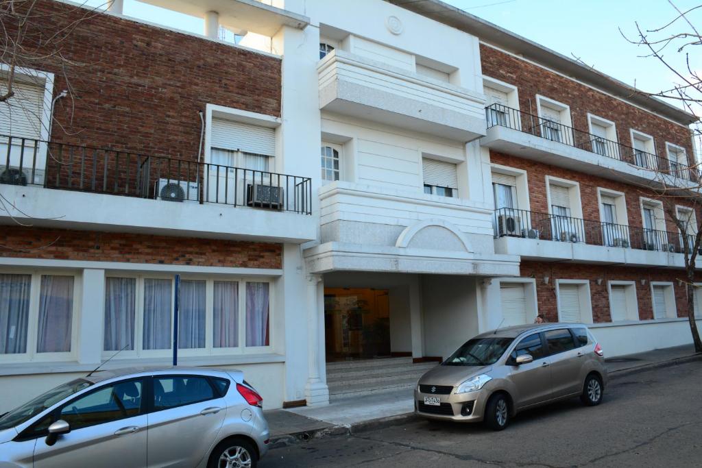 dos coches estacionados frente a un edificio en Hotel Crown en Melo