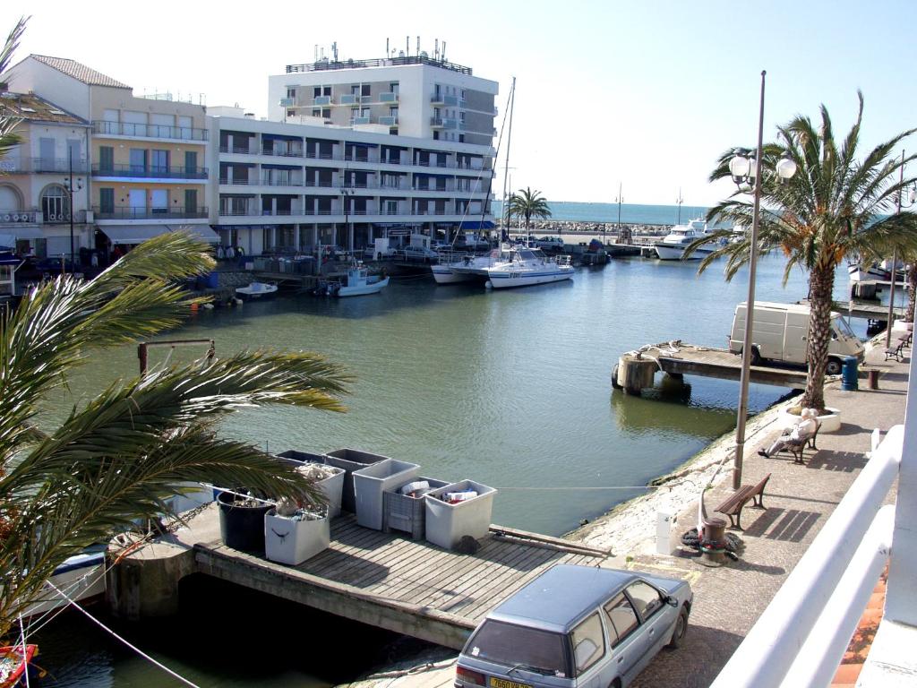 une voiture garée sur un quai à côté d'une rivière avec des bateaux dans l'établissement Villa d'architecte vue port à 2 pas de la plage, au Grau-du-Roi