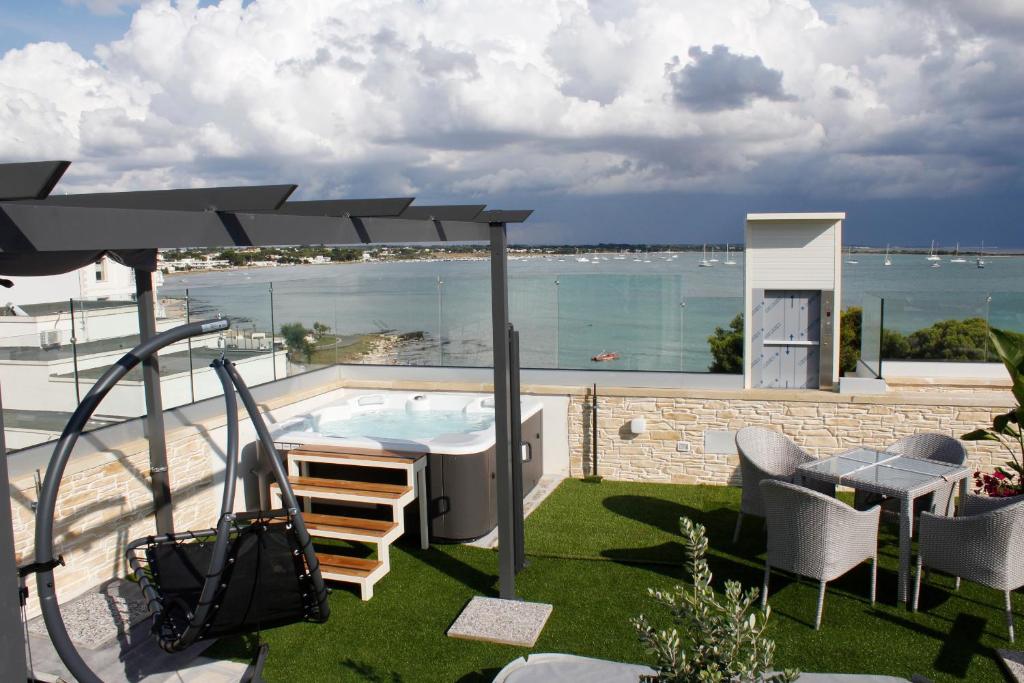 a patio with a hot tub and a view of the ocean at Hotel Royal - Beauty & Spa in Porto Cesareo