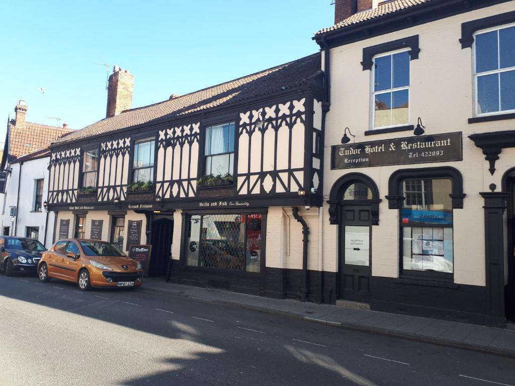 ein orangefarbenes Auto, das vor einem Gebäude geparkt ist in der Unterkunft The Tudor Hotel in Bridgwater