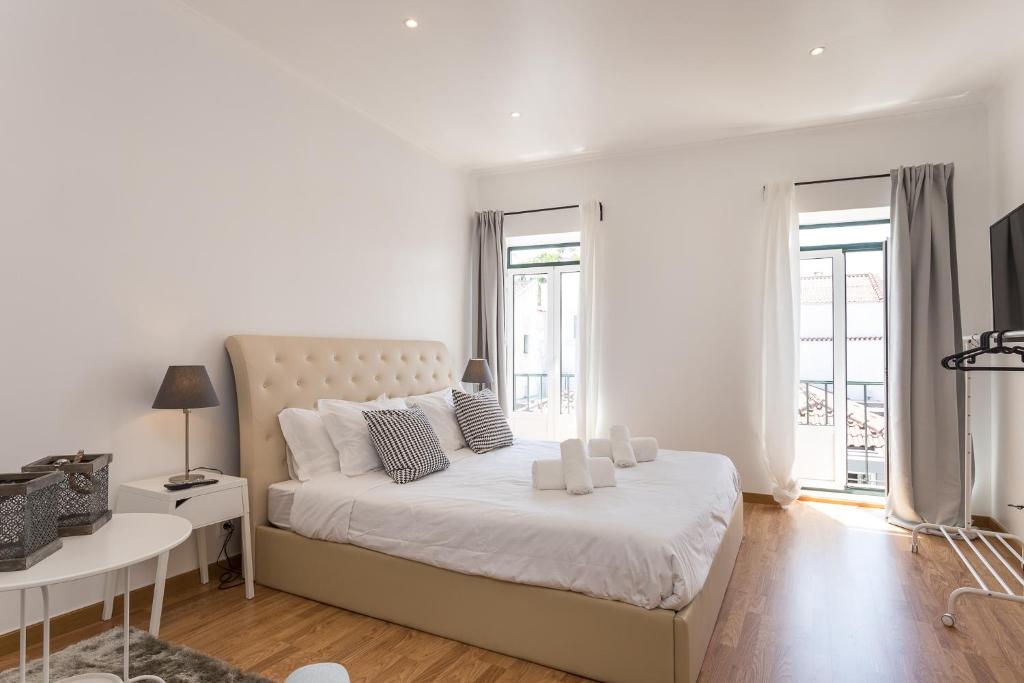 een witte slaapkamer met een groot bed en een tafel bij World Travelers in Lissabon