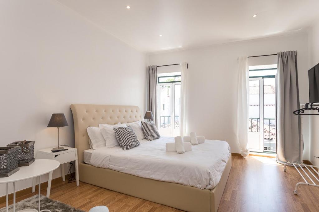 a white bedroom with a large bed and a table at World Travelers in Lisbon