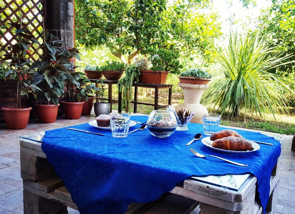 un tavolo con una tovaglia blu e del cibo sopra di Agriturismo Sa Pramma a Santa Maria la Palma