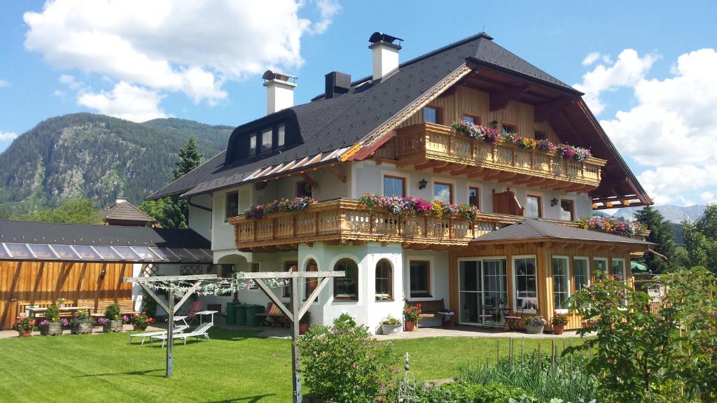a large house with a balcony with flowers on it at Ferienwohnungen Haus-Holzer in Mauterndorf