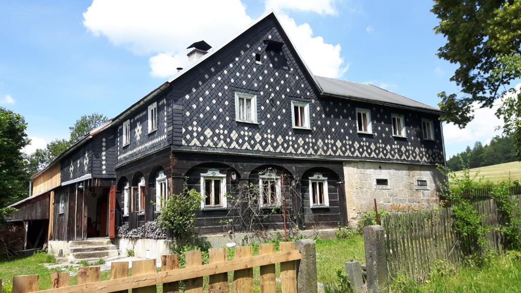 una vieja casa en blanco y negro con una valla en Prázdninový dům Nové Hraběcí, en Šluknov