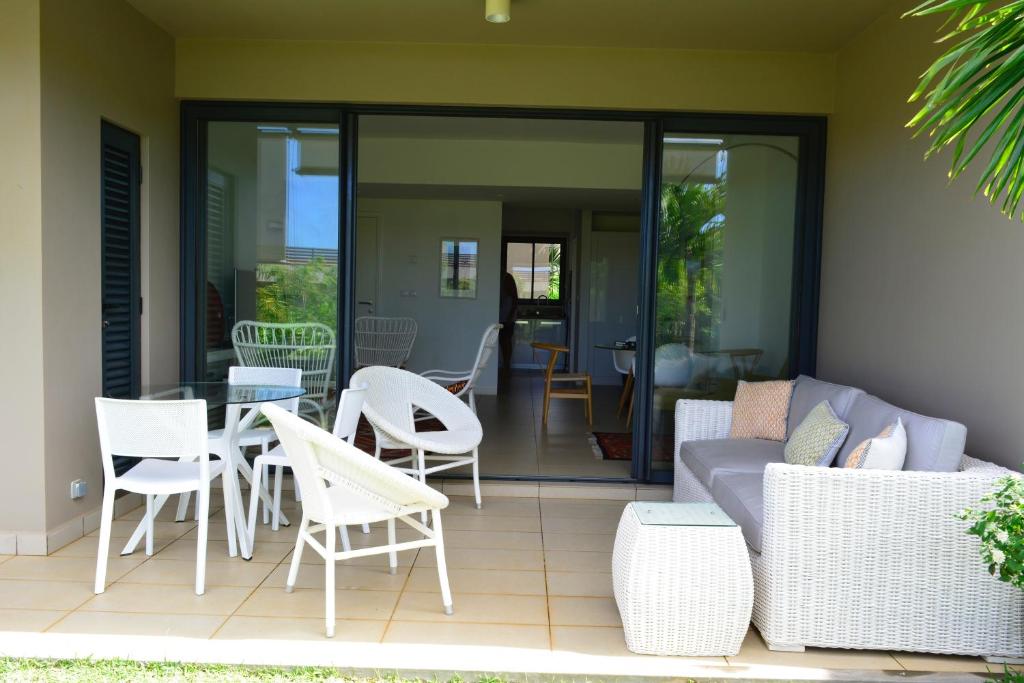 een patio met een bank, stoelen en een tafel bij AZURI Serviced Garden Apartment in Roches Noires