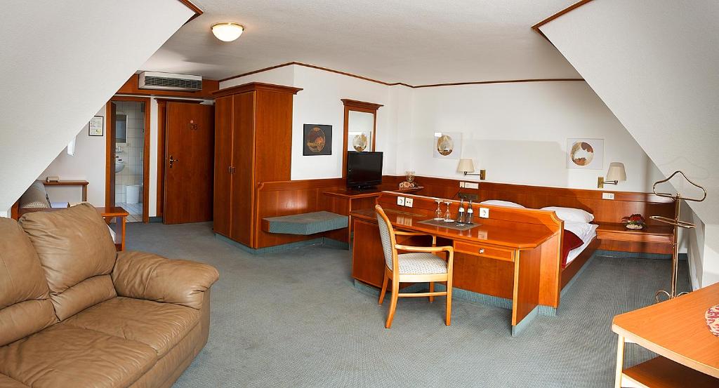 a room with a bed and a couch and a desk at Hotel Zeller Zehnt in Esslingen