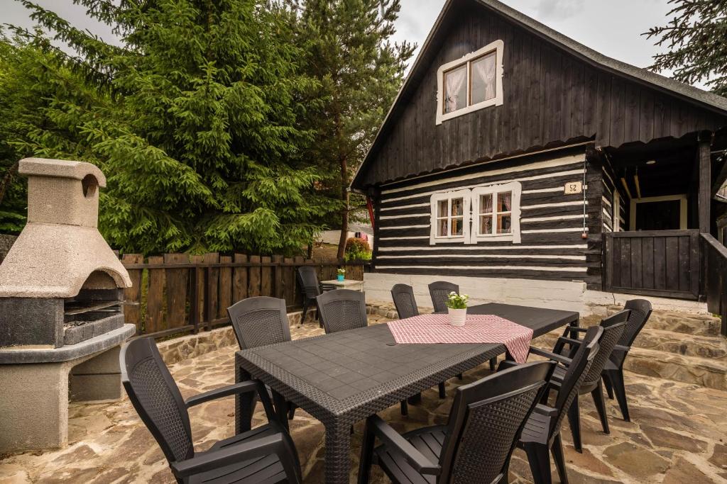 a table and chairs and a house with a fireplace at Narnia Relax House - Liptov in Liptovský Mikuláš