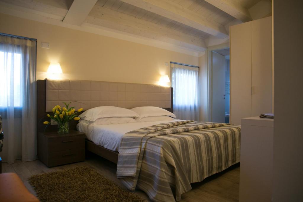 een slaapkamer met een groot bed met witte lakens en kussens bij Hotel Calinferno in Codognè