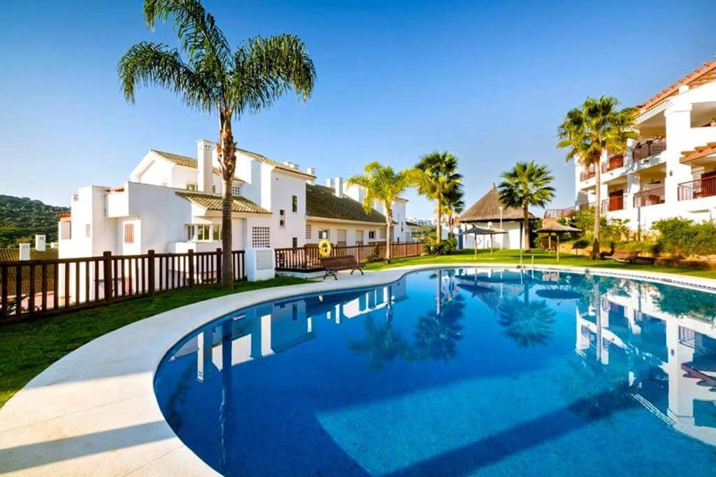 una piscina frente a una casa con palmeras en Alcaidesa Golf, en Alcaidesa